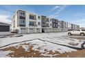 Two-story townhome building with attached garages and snowy landscape at 6153 N Ceylon St # 201, Denver, CO 80249