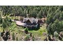 Breathtaking aerial view of a secluded log home nestled among the trees, offering privacy and serene mountain living at 13525 Woodmoor West Dr, Larkspur, CO 80118