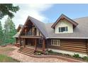 Inviting log home with stone pathway, covered porch and custom railings welcomes you to mountain living at its finest at 13525 Woodmoor West Dr, Larkspur, CO 80118