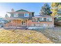 Rear exterior featuring a brick facade, a deck, a well-kept lawn and mature trees at 7649 E Amherst Ave, Denver, CO 80231