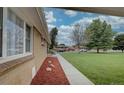 Tan brick multi-unit dwelling sits in a green manicured lawn and blue sky overhead at 3376 Jasmine St, Denver, CO 80207