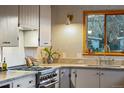 Bright kitchen with a gas range, stone countertops, wood window trim, and a brass faucet for a modern touch at 8120 W 54Th Pl, Arvada, CO 80002