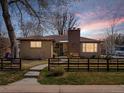 Charming home with a brick chimney and fenced front yard at sunset at 1594 S Locust St, Denver, CO 80224