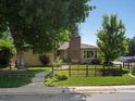 Quaint home with a brick chimney, well-manicured lawn and garden, and inviting walkway to the front door at 1594 S Locust St, Denver, CO 80224