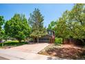 Exterior view of the property, showcasing the garage, driveway, and mature trees at 6360 S Kendall St, Littleton, CO 80123