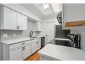 Modern kitchen with white cabinetry, gray backsplash, stainless steel appliances, quartz counters and skylight above at 1830 Newland Ct # 319, Lakewood, CO 80214