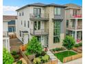 Contemporary three-story home featuring a stone facade, multiple balconies, and a well-manicured yard with a wooden fence at 21345 E 59Th Dr, Aurora, CO 80019
