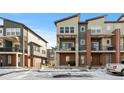 Modern townhomes with brick accents, balconies, and snow-covered landscaping present an attractive exterior view at 7856 W 43Rd Pl, Wheat Ridge, CO 80033