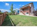 Spacious backyard with a deck, a wooden fence, a shed, and a lush green lawn at 6147 N Flanders St, Aurora, CO 80019