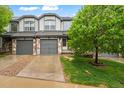 Beautiful townhome featuring stone accents, gray siding, attached garage, and a lovely tree at 2002 E 102Nd Cir, Thornton, CO 80229
