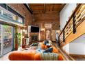 Inviting living room with exposed brick, wood beams, fireplace, and a comfortable orange velvet sofa at 3033 Blake St # 109, Denver, CO 80205