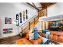 Open-concept living room featuring exposed wood beams, an open staircase, and comfortable seating at 3033 Blake St # 109, Denver, CO 80205