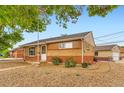 Quaint brick home with low-maintenance landscaping, featuring gravel and green shrubbery near the house at 6930 Warren Dr, Denver, CO 80221