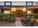 Covered front porch with decorative lighting and secure entry, surrounded by lush greenery at 1998 S Harlan Ct, Lakewood, CO 80227