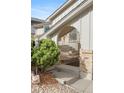 Inviting front entrance with stone steps, brick columns, green bush, and a stylish metal railing at 3765 S Depew St, Denver, CO 80235