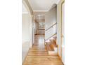 Bright hallway with polished hardwood floors leading to a staircase and other rooms in the house at 3765 S Depew St, Denver, CO 80235