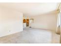 Large living room featuring neutral walls and carpets, partially open to the kitchen at 2180 S Flower Way, Lakewood, CO 80227