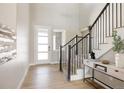 Bright foyer with hardwood floors, black iron stair railing, and a modern front door at 14247 Beebalm Loop, Parker, CO 80134