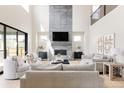 Spacious living room with soaring ceilings, tile fireplace, large windows, and neutral furnishings at 14247 Beebalm Loop, Parker, CO 80134