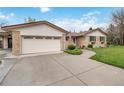 Spacious driveway leads to a brick home with an attached garage and a well-maintained lawn at 6288 S Harlan Way, Littleton, CO 80123