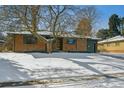 Ranch style brick home with mature trees and snow covered yard at 725 S Harrison St, Denver, CO 80209