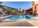 Community pool with lounge chairs and well-maintained landscaping and city views in the background at 100 Park W Ave # 1403, Denver, CO 80205