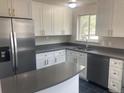 Bright kitchen boasts stainless steel appliances, grey countertops, and stylish white cabinetry at 1326 S Canosa Ct, Denver, CO 80219