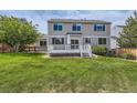 Expansive backyard featuring a well-kept lawn, mature trees, privacy fence, and a deck with stairs at 3416 Hawthorne Dr, Highlands Ranch, CO 80126