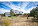 A sprawling backyard with a deck, green lawn, trees, and a garden with bright flowers at 19052 E Briarwood Dr, Centennial, CO 80016