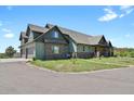 Two-story home boasts a stone facade, three-car garage and lush front lawn on a sunny day at 5800 Elk View Ct, Larkspur, CO 80118