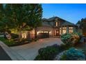 Charming home with a stone and stucco exterior, well-manicured landscaping, and an attached garage at dusk at 35 Brookhaven Pl, Littleton, CO 80123