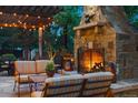 Cozy outdoor stone fireplace with comfortable seating beneath a pergola with string lights at 35 Brookhaven Pl, Littleton, CO 80123