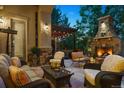 Inviting outdoor patio with a stone fireplace, comfortable seating, pergola, and ambient lighting at 35 Brookhaven Pl, Littleton, CO 80123