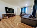Comfortable living room with wood floors, a large TV, and a cozy couch at 6710 Clermont St, Commerce City, CO 80022