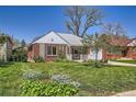 Classic brick home featuring a well-kept lawn, inviting porch, and mature trees in the yard at 5703 Ammons St, Arvada, CO 80002