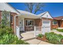 Inviting brick home showcasing a quaint front porch with outdoor seating and garden at 5703 Ammons St, Arvada, CO 80002