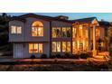 Close-up of an elegant two-story home featuring tall windows and a grand entrance with columns at twilight at 5799 Crestbrook Cir, Morrison, CO 80465