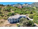 A home with a tile roof sits amidst lush greenery, showcasing the property's serene and secluded setting at 5799 Crestbrook Cir, Morrison, CO 80465