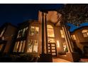 Eye-level view of a home's grand entrance with prominent columns and floor-to-ceiling windows at nighttime at 5799 Crestbrook Cir, Morrison, CO 80465