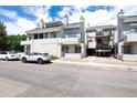 Condominium building exterior with balconies, covered parking, and central staircase, set against a blue sky at 1830 Newland Ct # 321, Lakewood, CO 80214