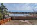Private backyard with mature trees, fire pit, and fenced yard overlooking tranquil pond at 4328 S Carr Ct, Littleton, CO 80123