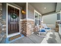 Inviting front porch with rocking chairs and stylish stone accents around the front door at 23879 E Narrowleaf Pl, Aurora, CO 80016