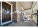 Inviting front porch with stone accents, rocking chairs, and a charming wreath on the front door at 23879 E Narrowleaf Pl, Aurora, CO 80016