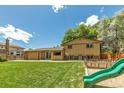 Expansive backyard with lush green lawn, mature trees, and a playset at 8272 Ammons Cir, Arvada, CO 80005