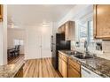 Functional kitchen featuring a stainless steel sink, granite countertops, and wooden cabinetry at 1364 Lansing St, Aurora, CO 80010