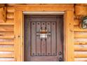 A rustic, wood-paneled front door features dark hardware and a small, barred window at 5724 Highway 9, Breckenridge, CO 80424
