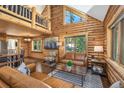 Bright, wood-clad living room featuring vaulted ceilings, cozy furniture, and views of the outdoors at 5724 Highway 9, Breckenridge, CO 80424