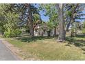 Charming home with large trees, inviting front porch, and well-maintained lawn at 7801 Valley View St, Louviers, CO 80131