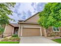 Home exterior with attached two-car garage, tan siding and some stone trim at 6068 W Utah Ln, Lakewood, CO 80232