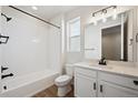 A clean bathroom featuring white fixtures, a shower-tub combo and modern vanity lighting at 1392 Rock Cliff Ave, Erie, CO 80516